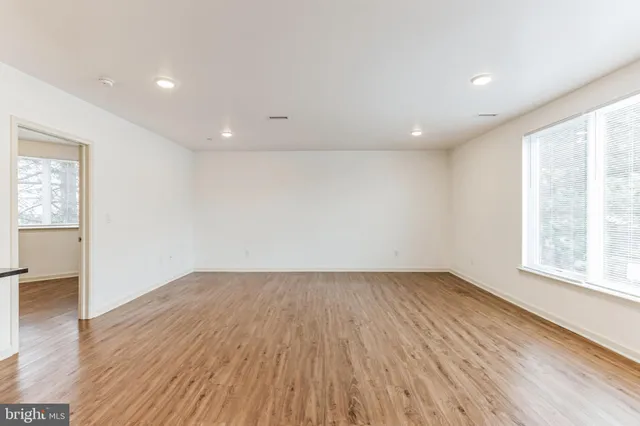 an empty room with wooden floor and windows