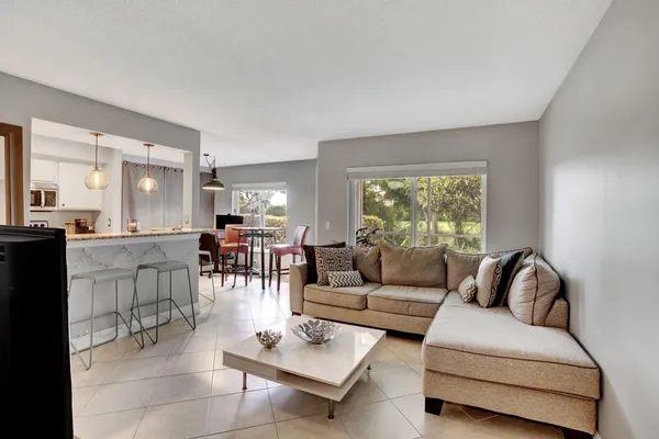 a large kitchen with granite countertop a stove a sink a window and chairs