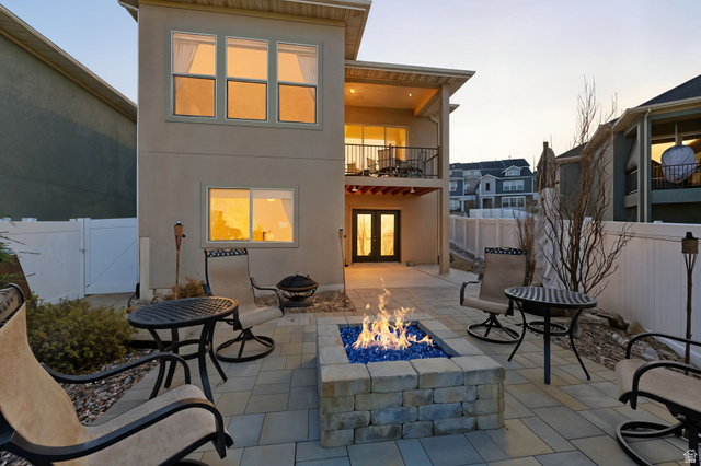 987 East Deer Arch Lane Draper, UT 84020 - Photo 2 of 46 Back of house at dusk with french doors, a balcony, stucco siding, a fenced backyard with fire pit