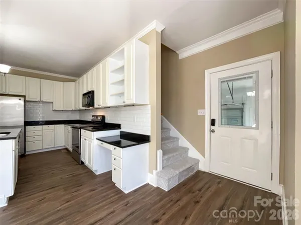 a kitchen with granite countertop a refrigerator and a stove top oven
