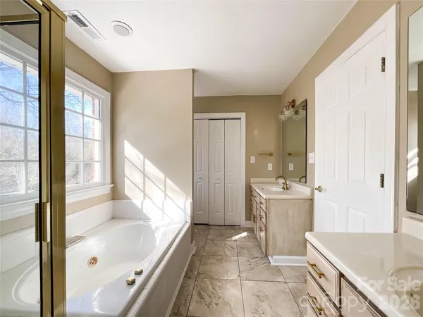 a bathroom with a granite countertop sink a bathtub and window