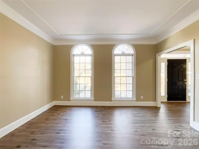 an empty room with wooden floor and windows with curtains view