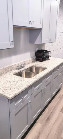 a kitchen with granite countertop white cabinets and a sink