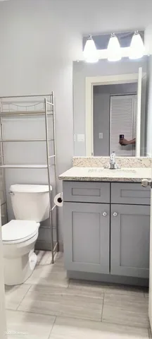 a bathroom with a granite countertop sink vanity mirror and toilet