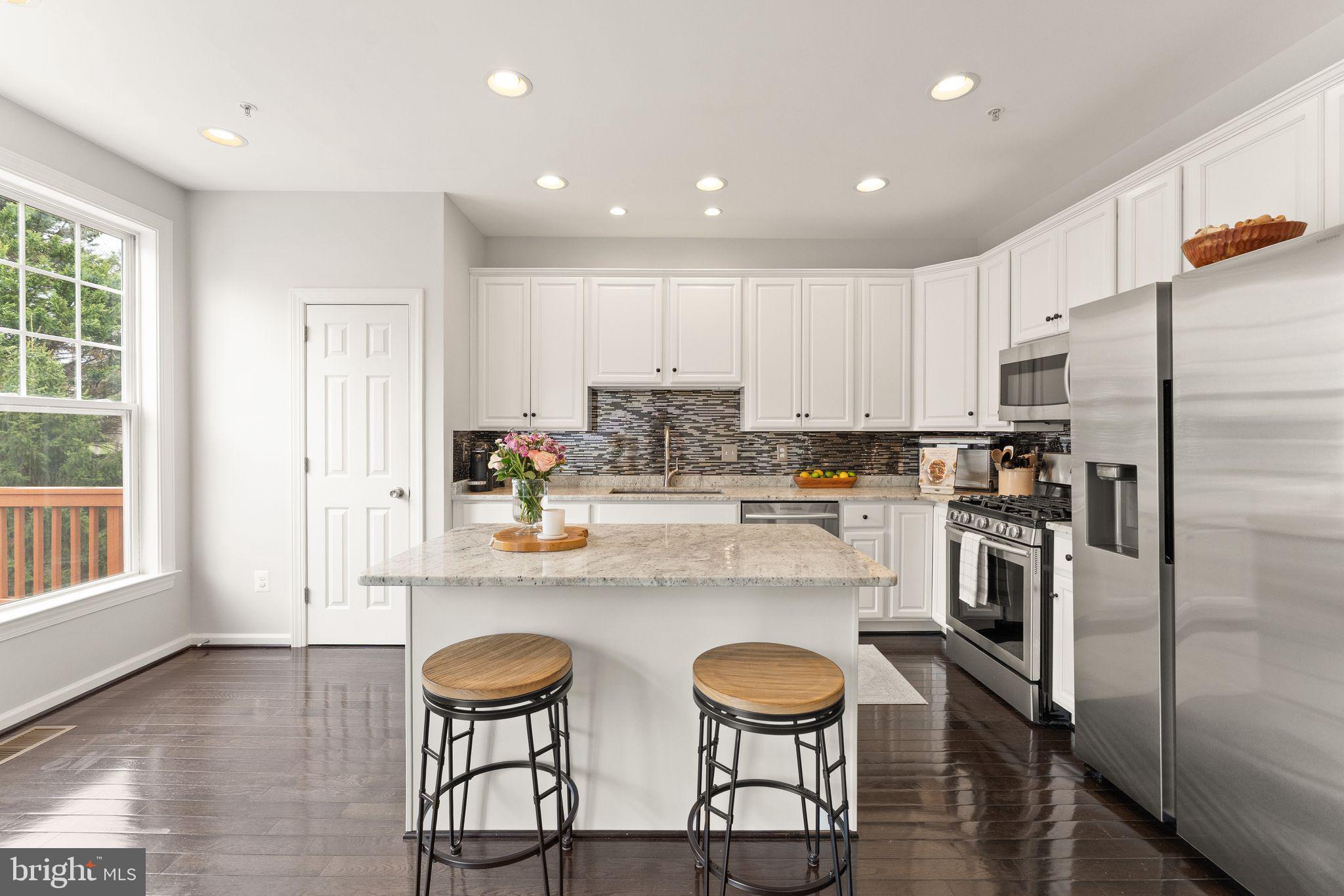 18168 Mill House Square Leesburg, VA 20176 - Photo 12 of 60 a kitchen with stainless steel appliances granite countertop a stove a sink a refrigerator and white cabinets with wooden floor
