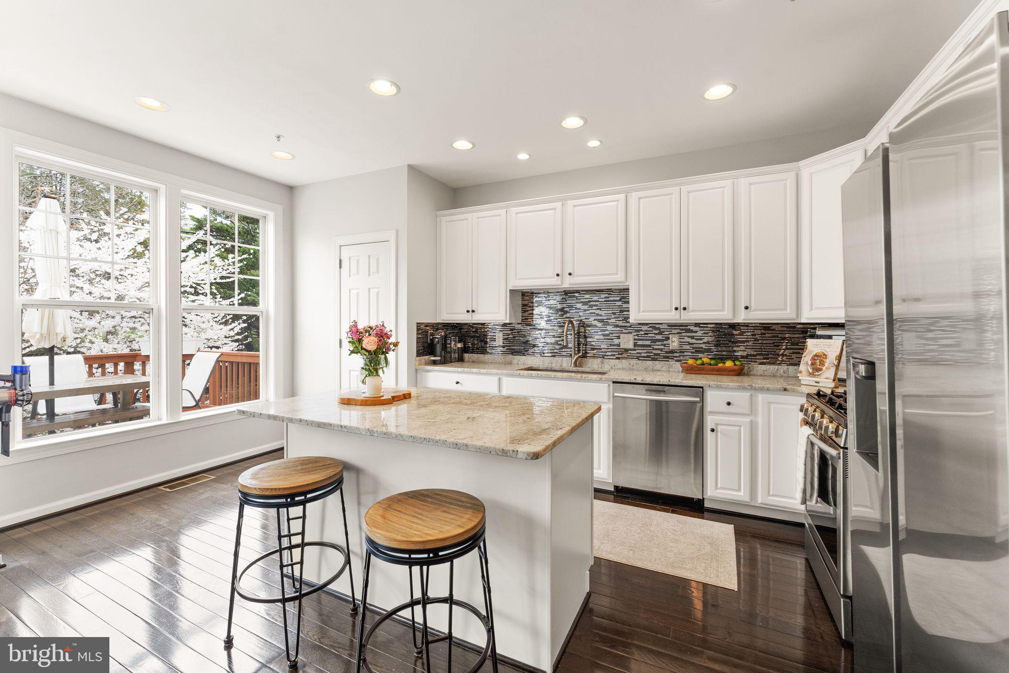 18168 Mill House Square Leesburg, VA 20176 - Photo 13 of 60 a kitchen with stainless steel appliances granite countertop a stove a sink refrigerator and white cabinets with wooden floor
