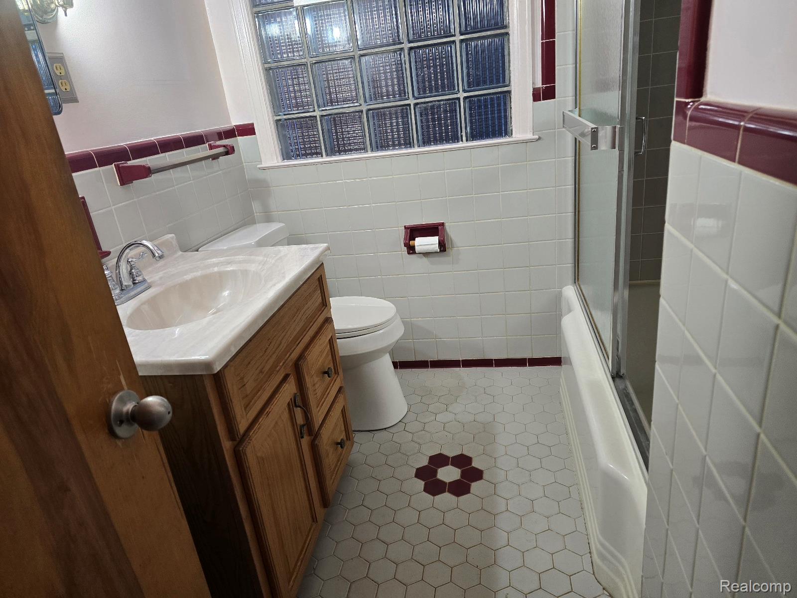 803 Commonwealth Avenue Flint, MI 48503 - Photo 11 of 15 Full bathroom featuring vanity, tile walls, enclosed tub / shower combo, and a wainscoted wall