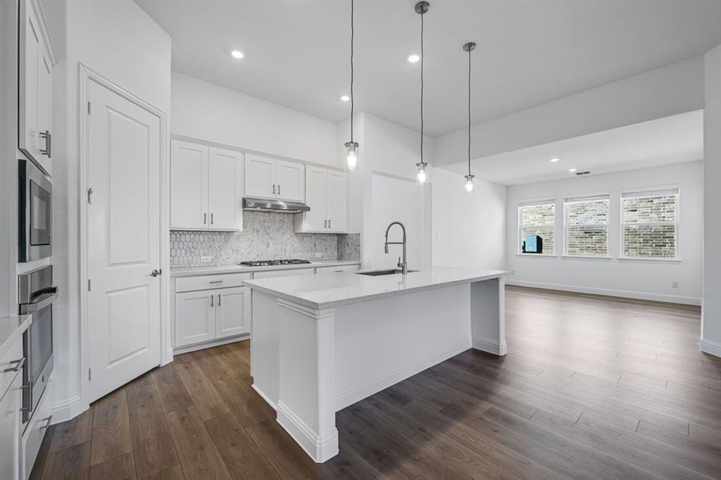 331 Trillium Street Oak Point, TX 75068 - Photo 11 of 36 a kitchen with stainless steel appliances granite countertop a refrigerator a sink dishwasher a stove and white cabinets with wooden floor