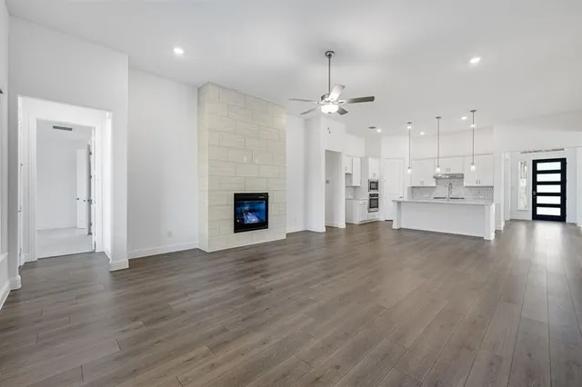 a view of empty room with wooden floor and kitchen view