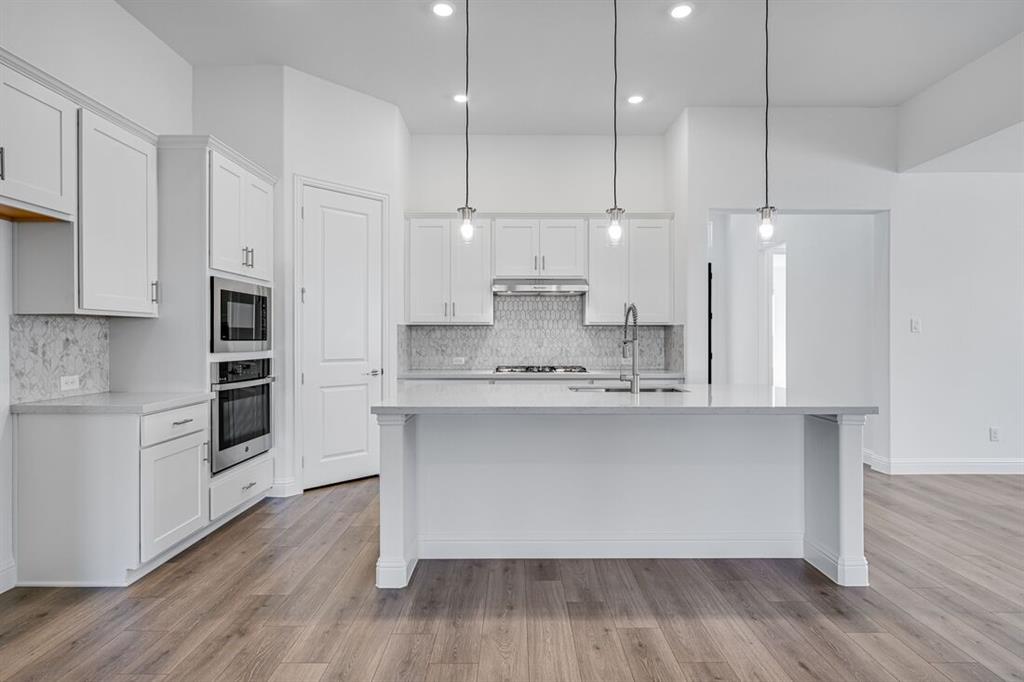 331 Trillium Street Oak Point, TX 75068 - Photo 2 of 36 a kitchen with stainless steel appliances granite countertop a sink a stove a refrigerator and white cabinets with wooden floor