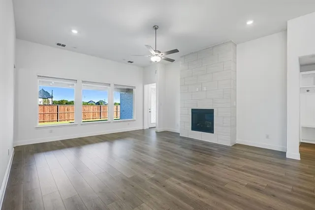 an empty room with wooden floor fireplace and windows