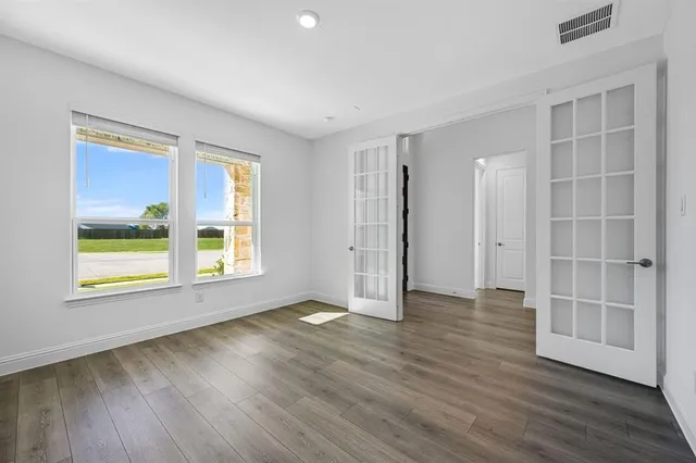 an empty room with wooden floor and windows