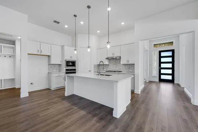 a large kitchen with cabinets wooden floor and stainless steel appliances
