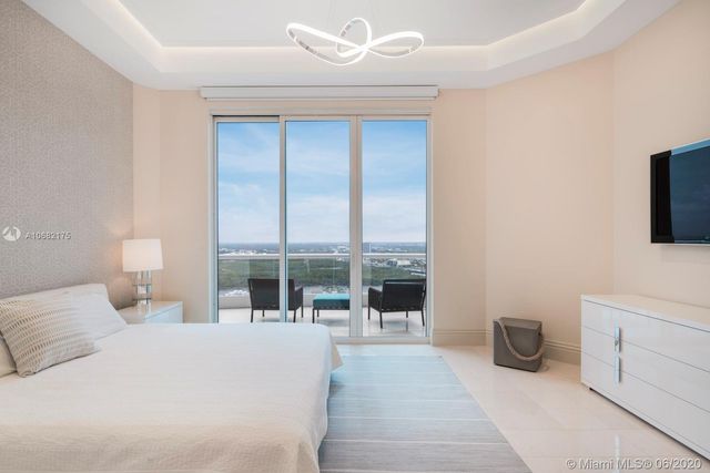 a bedroom with a bed a large window and mirror