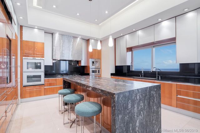 a large kitchen with granite countertop a large counter top space and stainless steel appliances