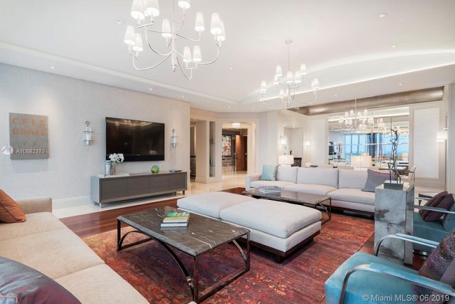a living room with furniture a flat screen tv and a chandelier