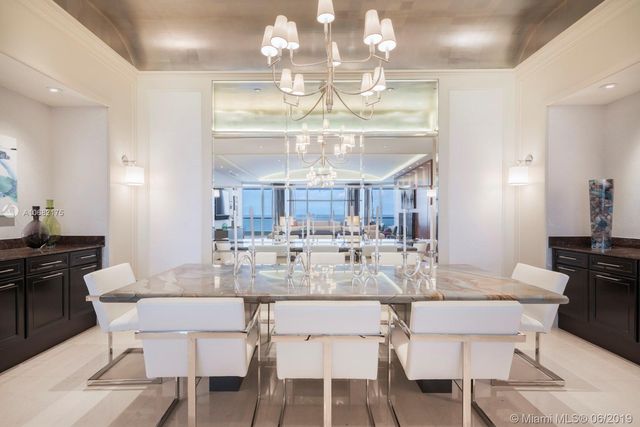 a view of a dining room with furniture a chandelier and kitchen view