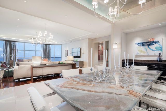 a large white kitchen with lots of counter space and chandelier