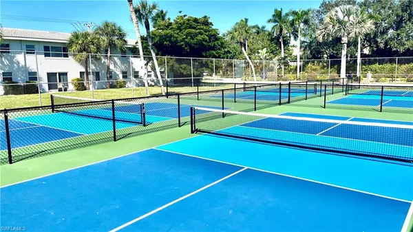 a view of a tennis ground with large trees