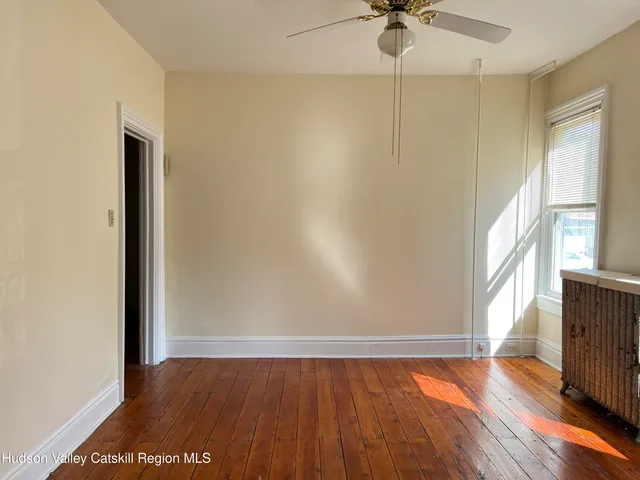 a view of an empty room with a window and wooden floor