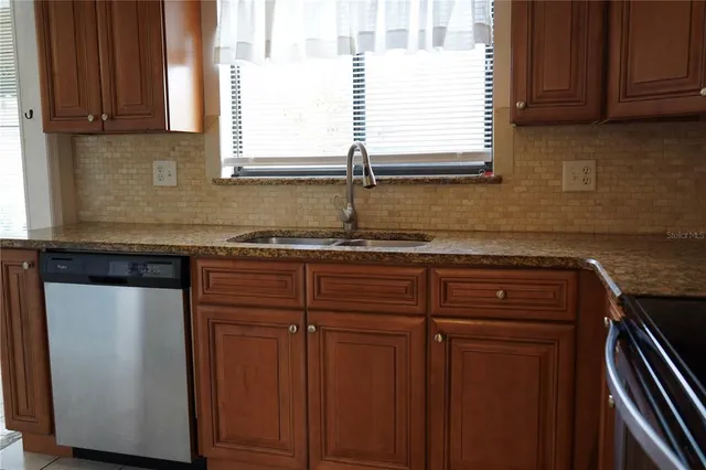 a kitchen with granite countertop cabinets sink and window