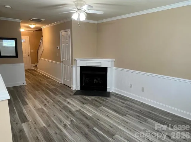 a view of an empty room with wooden floor and a fireplace