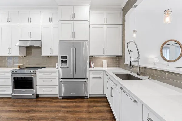 a kitchen with stainless steel appliances white cabinets and wooden floor