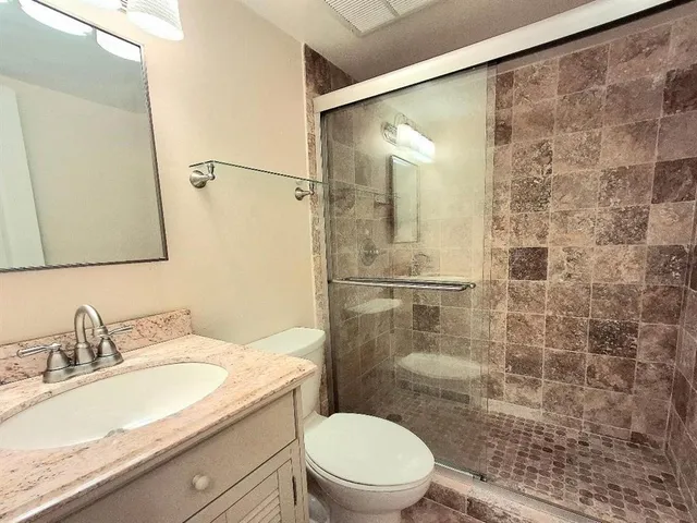 a bathroom with a granite countertop sink toilet and shower