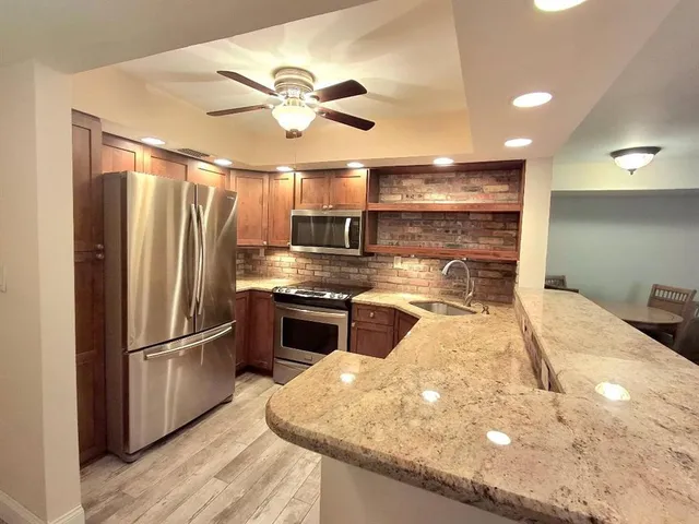a kitchen with stainless steel appliances granite countertop a refrigerator a sink and a stove