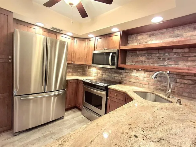 a kitchen with stainless steel appliances granite countertop a refrigerator a sink and a stove