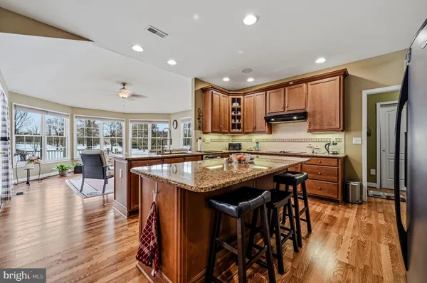 a open kitchen with stainless steel appliances granite countertop a table chairs and a refrigerator