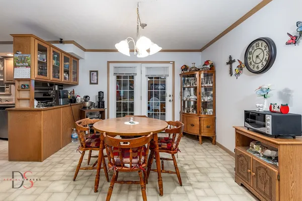 a view of a dining room with furniture a chandelier and kitchen view