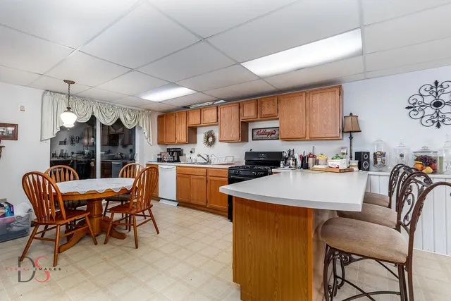 a kitchen with stainless steel appliances kitchen island granite countertop a table chairs sink and cabinets