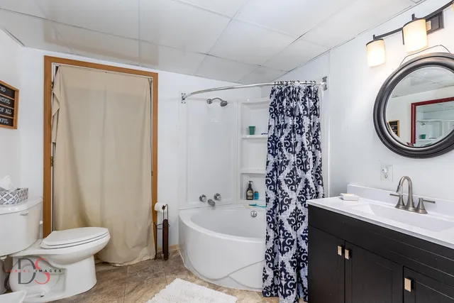 a bathroom with a bathtub shower sink mirror and toilet