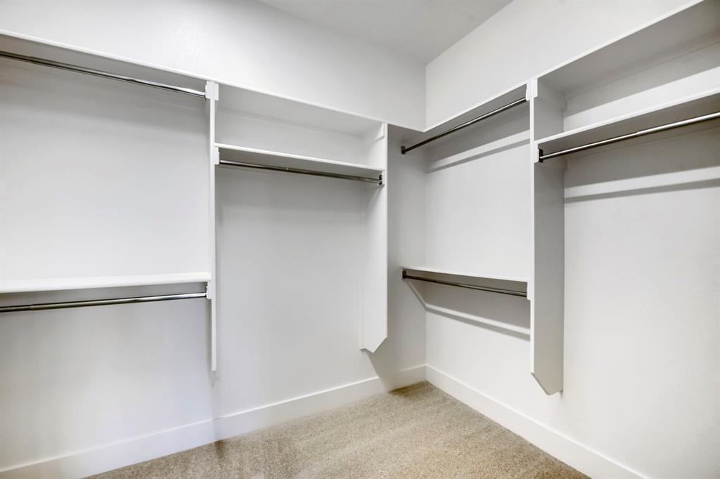 11548 Wulstone Road Haslet, TX 76052 - Photo 16 of 26 Walk-in closet featuring white built-in shelving, multiple hanging rods, and light-toned carpet flooring