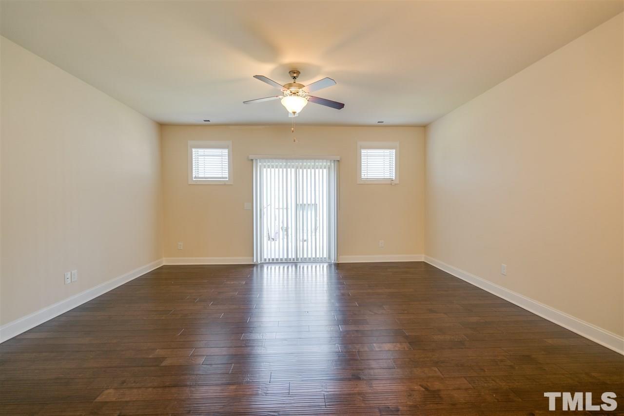 3950 Amelia Park Drive Raleigh, NC 27606 - Photo 7 of 20 an empty room with wooden floor chandelier fan and windows