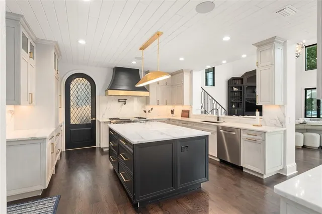 a kitchen with a sink dishwasher a stove and white cabinets with wooden floor
