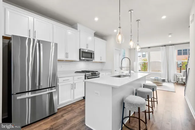 a kitchen with stainless steel appliances a refrigerator a sink a stove a dining table and chairs