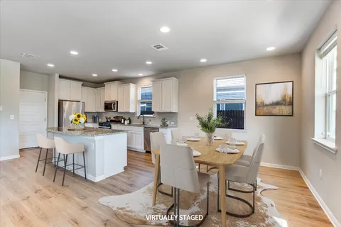 a kitchen with stainless steel appliances kitchen island granite countertop a dining table chairs and granite counter tops