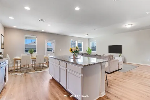 a kitchen with a sink and white cabinets with wooden floor