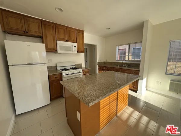 a kitchen with stainless steel appliances granite countertop a refrigerator a stove a sink a microwave and a refrigerator