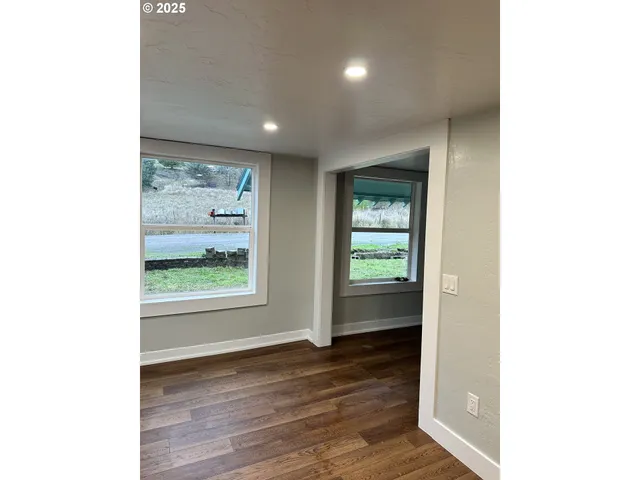 a view of an empty room with wooden floor and a window