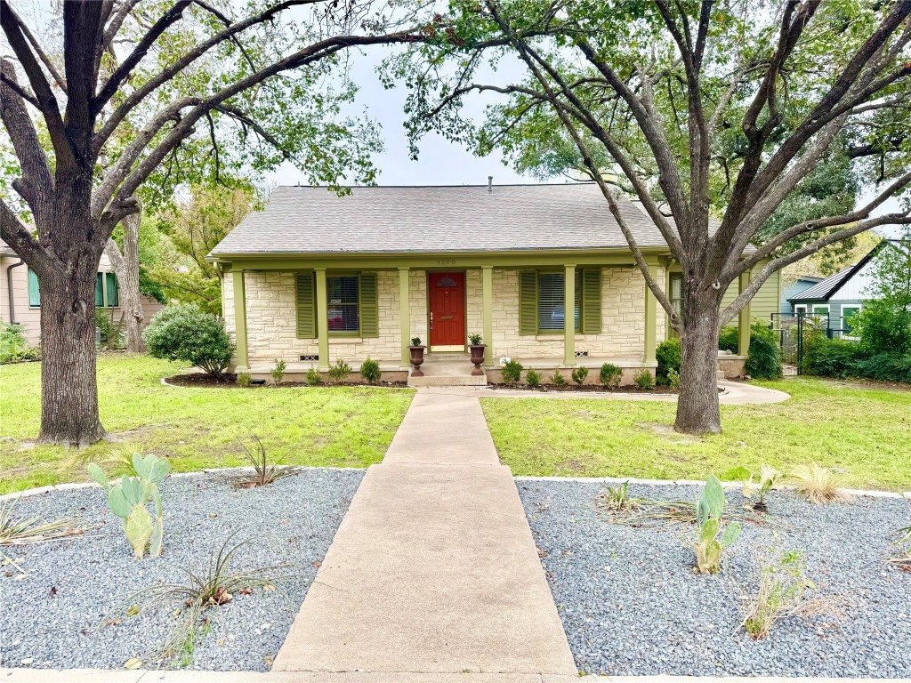 Ranch-style home with roof with shingles, stone siding, a front lawn, and a porch