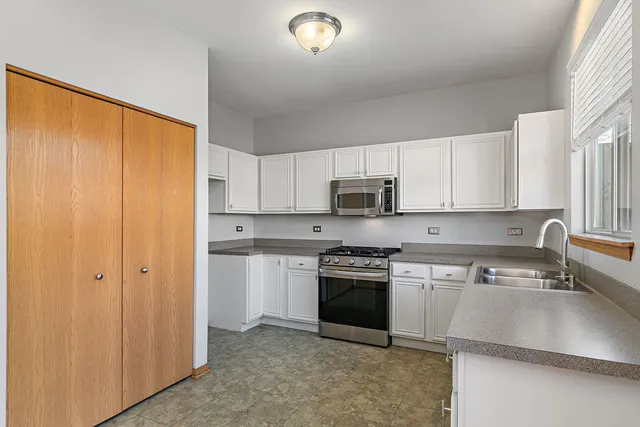 a kitchen with stainless steel appliances granite countertop a stove a sink and white cabinets