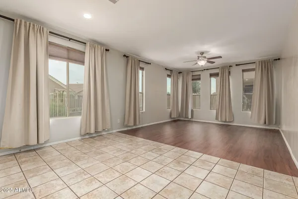 a view of an empty room with window and chandelier fan