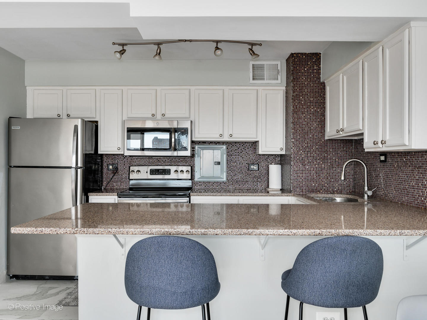 6030 North Sheridan Road, Unit 703 Chicago, IL 60660 - Photo 11 of 15 a kitchen with stainless steel appliances granite countertop a sink refrigerator and microwave