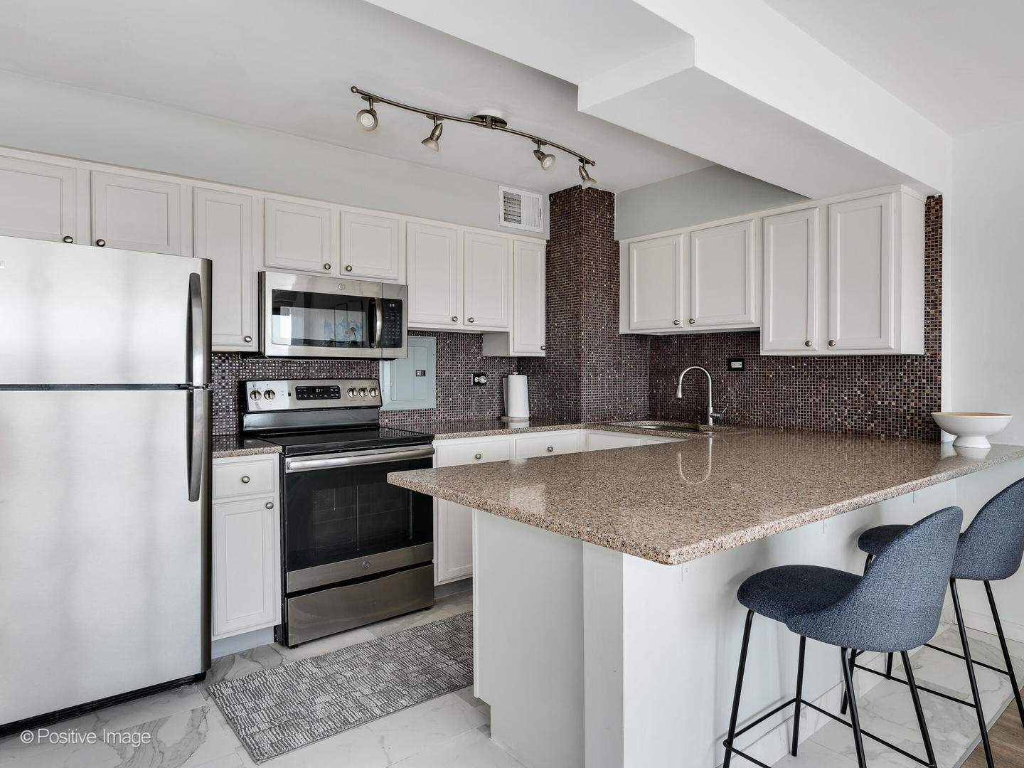 6030 North Sheridan Road, Unit 703 Chicago, IL 60660 - Photo 10 of 15 a kitchen with stainless steel appliances granite countertop a sink a stove a refrigerator a center island and cabinets