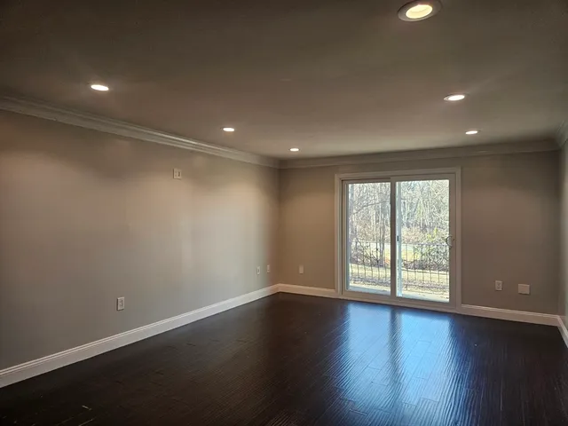 an empty room with wooden floor and windows with curtains