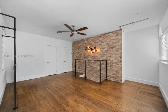 an empty room with wooden floor closet and windows