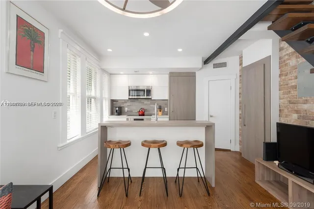 a kitchen with stainless steel appliances a dining table chairs microwave and sink